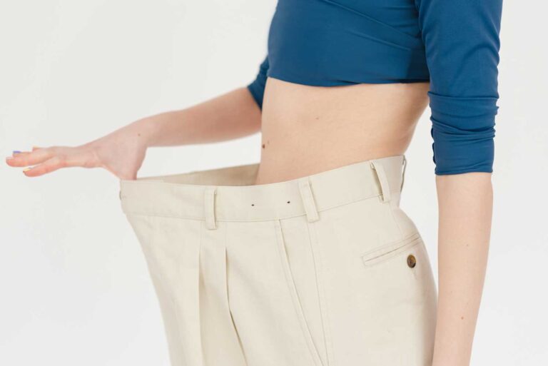 A Woman In Oversized Trousers Showing How To Lose The Weight Before Your Tummy Tuck